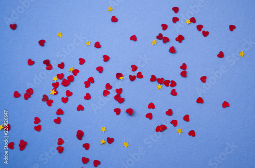 Beautiful heart and stars shaped red confetti on purple background.
