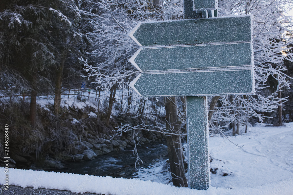 Fototapeta premium Three arrow signs pointing to the left in a winter landscape.