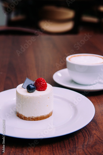 Creamy cheesecake with raspberry and blueberry on white dish in bekery cafe