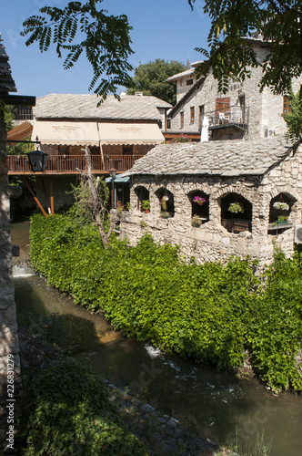 Wallpaper Mural Bosnia: lo skyline di Mostar, la città che prende il nome dai guardiani del ponte (mostari) che nel medioevo custodivano lo Stari Most (Ponte Vecchio), visto dalle acque verdi del fiume Narenta Torontodigital.ca