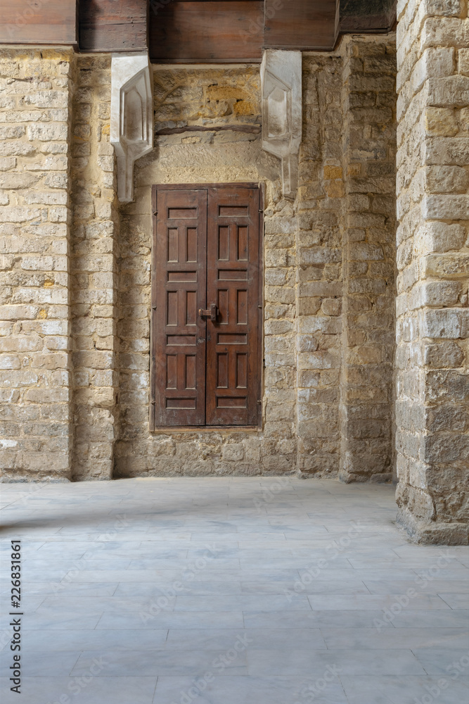 Fototapeta premium Facade of old abandoned stone bricks wall with grunge weathered wooden door, Old Cairo, Egypt