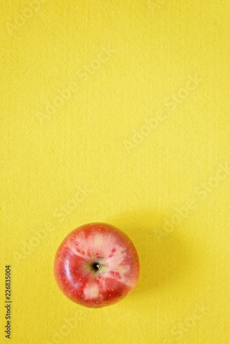 Red fresh apple on a yellow background. Close-up, copy space