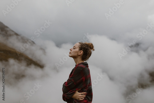 Woman above the clouds in the mountains