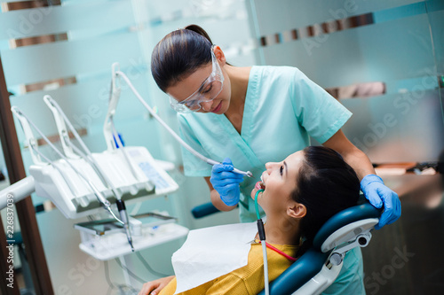 No pain in your teeth anymore! Dentist examining teeth of her beautiful patient in dentist’s office