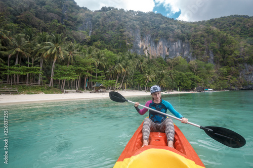 Woman paddling a kayak in the island mountains. Kayaking in El Nido, Palawan, Philippines.