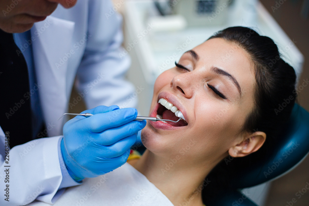 Last touch up. Close-up of dentist examining his beautiful patient in dentist’s office Last touch up. Close-up of dentist examining his beautiful patient in dentist’s office