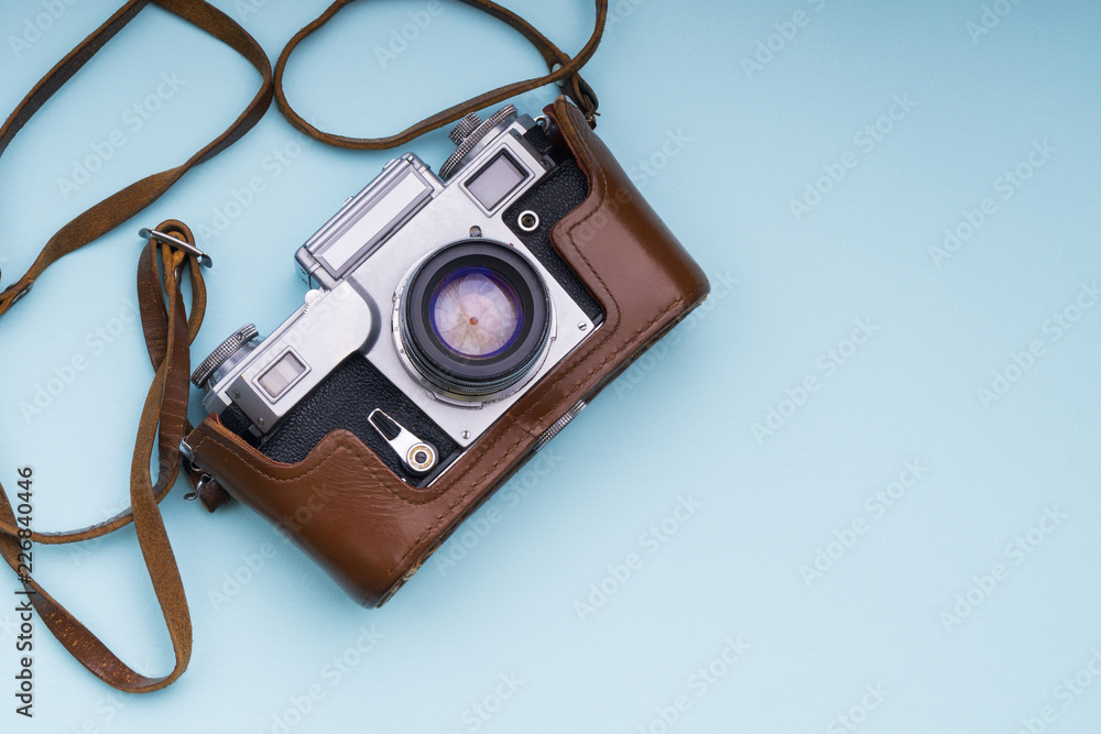 Old analog retro camera on blue background. Education photography courses back to school concept abstract wallpaper. Close up, top view, copy space. Old analog retro camera on blue background. Education photography courses back to school concept abstract wallpaper. Close up, top view, copy space.