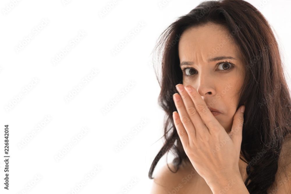 Caucasian girl with long dark hair expresses emotions of disgust and rejection. The girl in light clothes on a white background. The place for an inscription or the text. Horizontal shot Caucasian girl with long dark hair expresses emotions of disgust and rejection. The girl in light clothes on a white background. The place for an inscription or the text. Horizontal shot