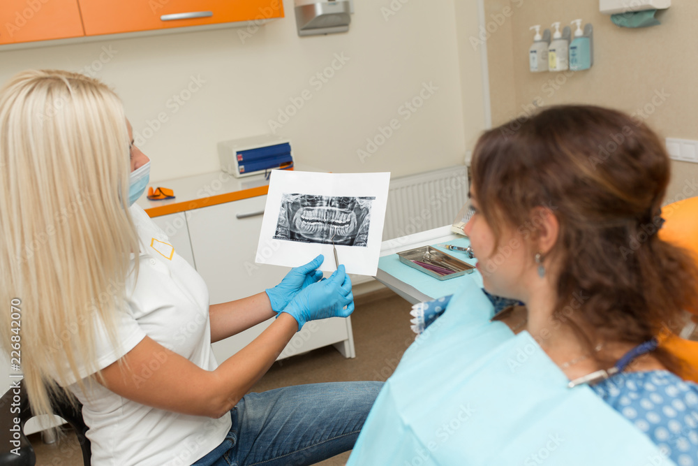 doctor dentist shows a client an x-ray picture of teeth - obrazy, fototapety, plakaty 
