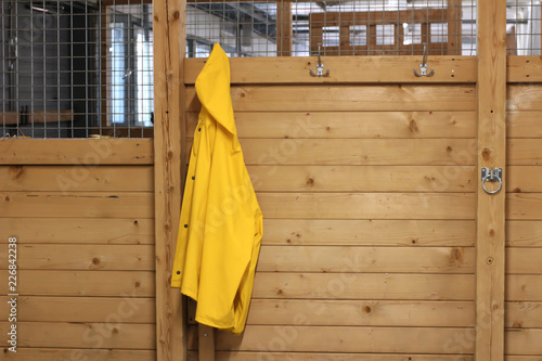 Yellow raincoat hanging in stable entrance © Jenny