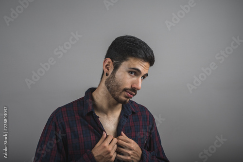 Young sexy man buttoning his shirt
