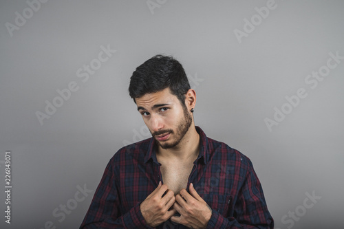 Young sexy man buttoning his shirt