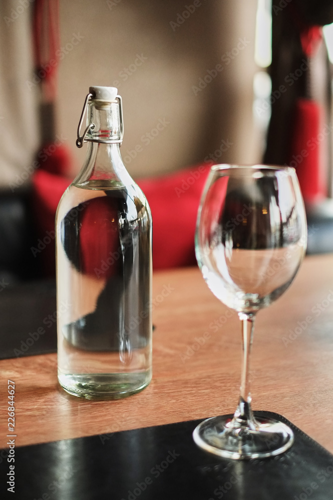 Tall glass bottle of water and an empty glass on a wooden table Tall glass bottle of water and an empty glass on a wooden table