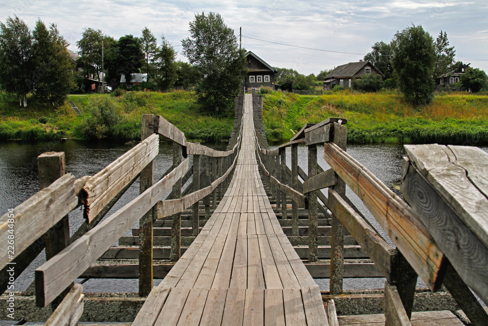 Old wooden suspension bridge over the river in the village Old wooden suspension bridge over the river in the village