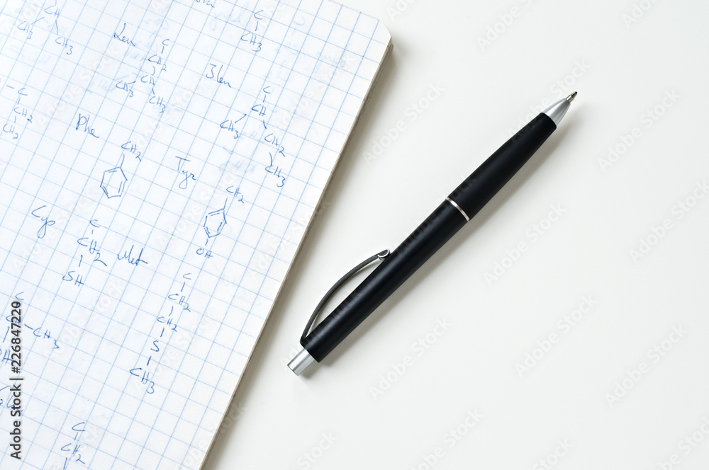 Notebook with chemical formulas and ballpoint pen on white table. Notebook with chemical formulas and ballpoint pen on white table.