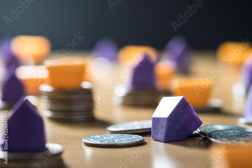 DARK TONE IMAGE OF SMALL PLASTIC HOUSE  COLLAPSES FROM STACKED MONEY COINS / BUSINESS AND FINANCIAL CONCEPT photo