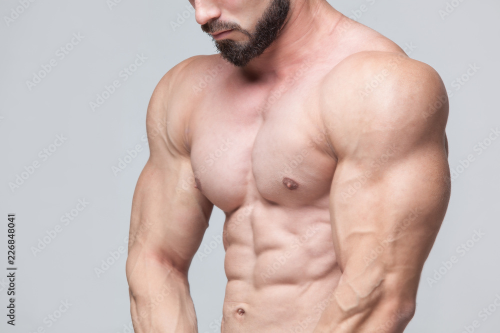 Strong Athletic Man Fitness Model Torso showing six pack abs. isolated on grey background with copyspace Strong Athletic Man Fitness Model Torso showing six pack abs. isolated on grey background with copyspace