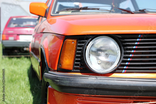 Exhibition of a retro cars. Big round headlight of a sports coupe bmw m3 e21.