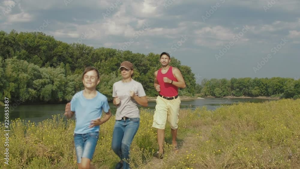 The family plays sports by the river. Parents with a child are engaged in fitness in nature. The family plays sports by the river. Parents with a child are engaged in fitness in nature.