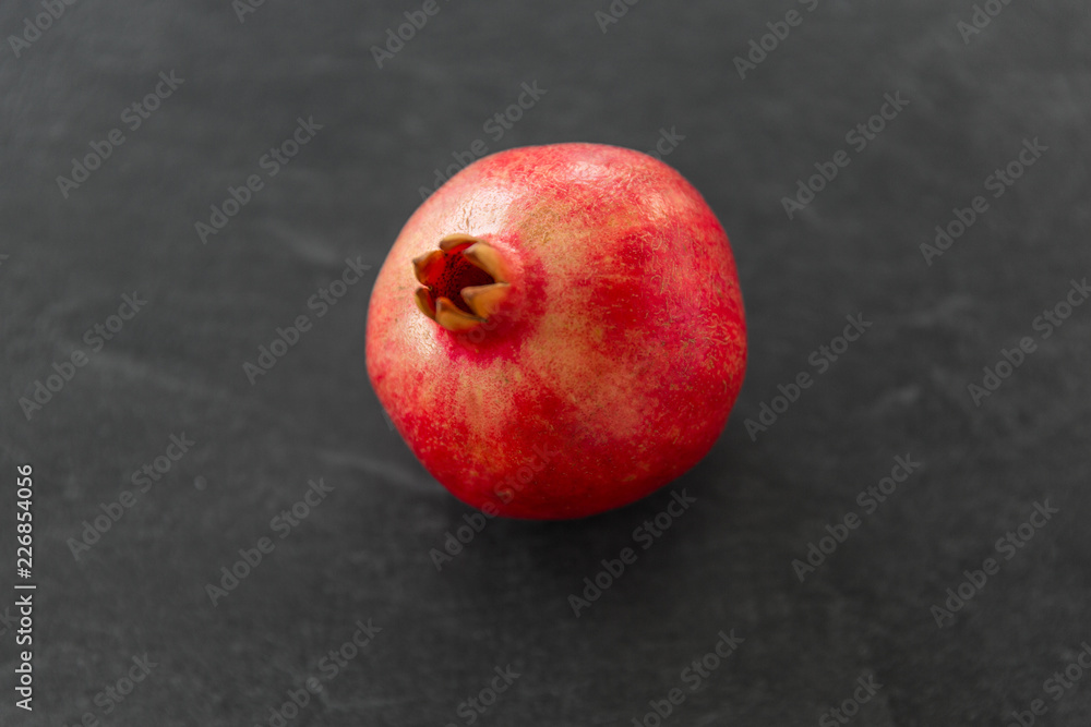 food, fruits and healthy eating concept - close up of pomegranate on stone table food, fruits and healthy eating concept - close up of pomegranate on stone table