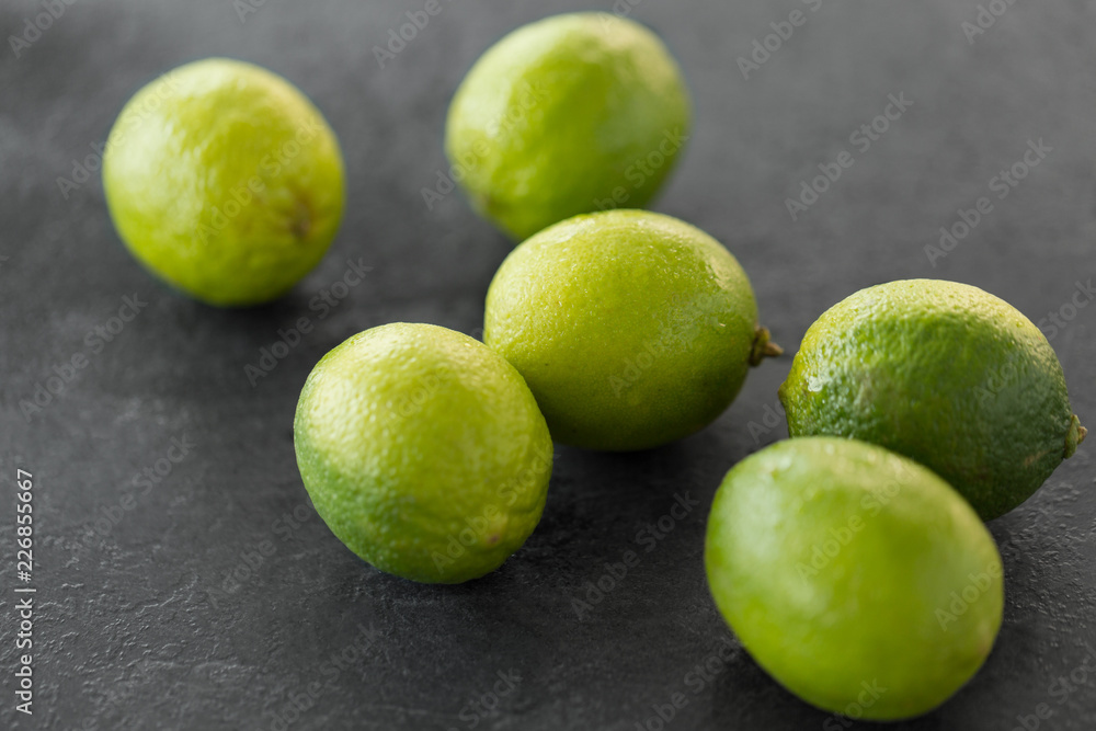 food, healthy eating and vegetarian concept - close up of whole limes on slate table top food, healthy eating and vegetarian concept - close up of whole limes on slate table top