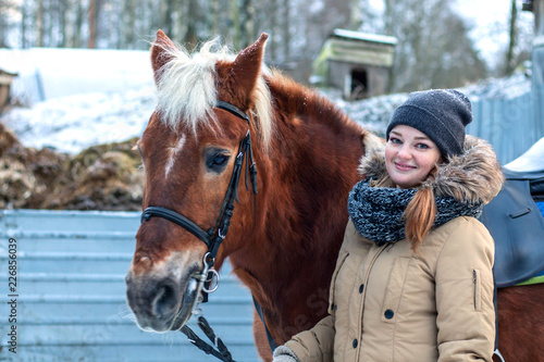 Cheerful nice girl with a horse. Country Equestrian Club. Winter trip out of town