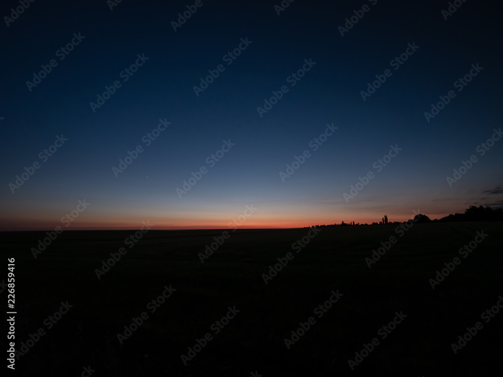 Beautiful summer sunset over the field. Colored sky by the sunset. Orange sunset sky. Beautiful summer sunset over the field. Colored sky by the sunset. Orange sunset sky.