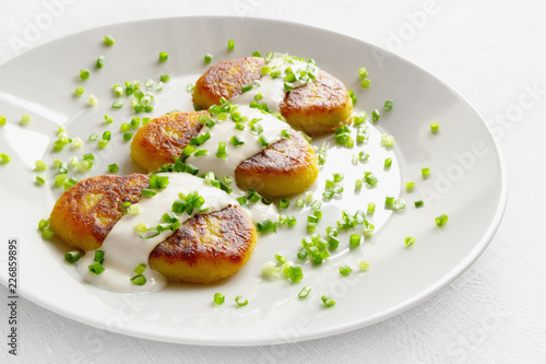 fried potato cutlets with sour cream decorated with onion