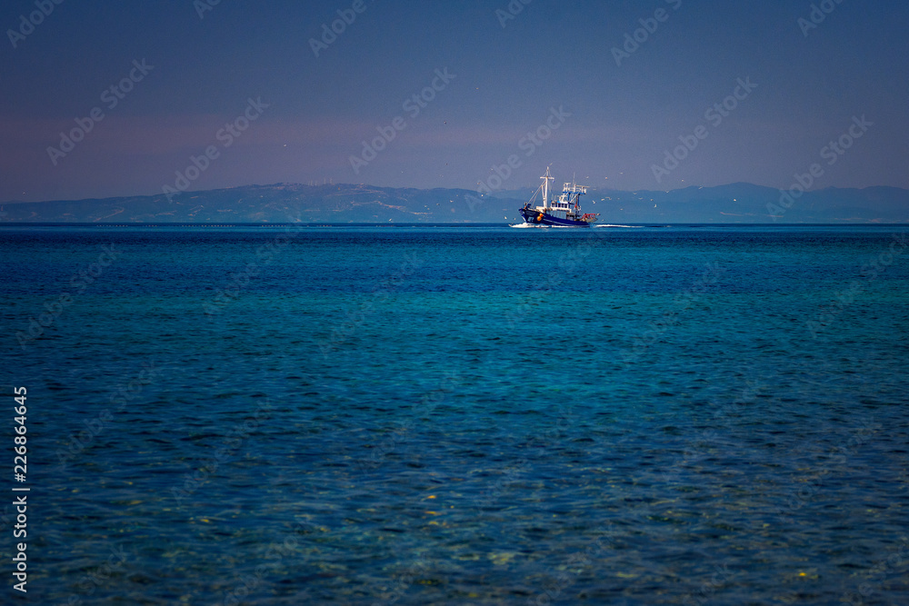 Fishing boat on the blue Aegean Sea in Samothrace Island in Greece with sea gulls surrounding it