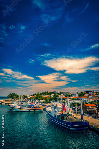 Kamariotissa port harbour on Samothrace Island in Greece during day with a vibrant sky and beautiful colors in the water with lots of boats at the pier