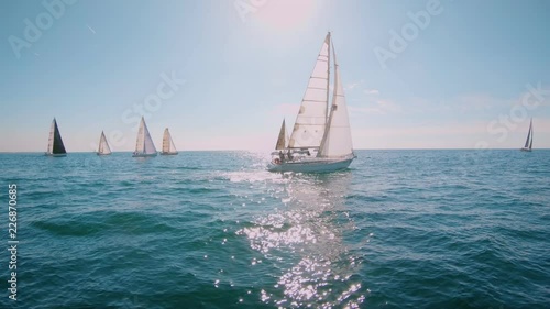 Slow motion shot of graceful and beautiful sailboat glide through blue turquoise calm water of sea or ocean. Amazing epic sailing race in mediterranean. European summer vacation dream