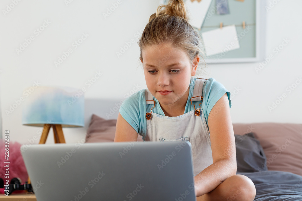 Cute girl using laptop in her bedroom Cute girl using laptop in her bedroom