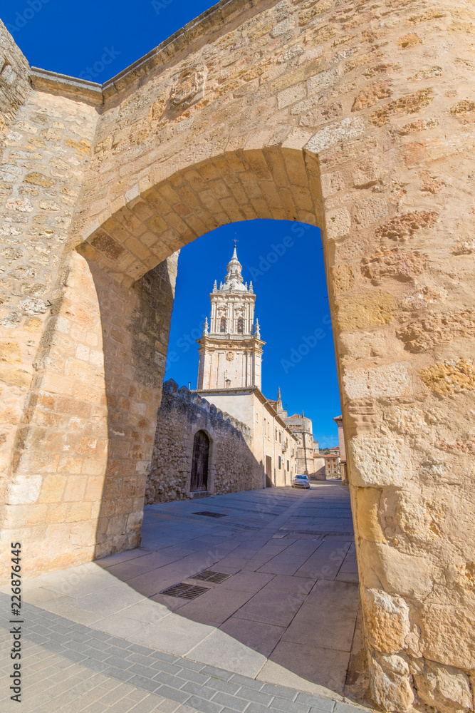 tower of cathedral of Burgo de Osma medieval town through the wall gate arch, public street, landmark and monument from thirteenth century, in Soria, Spain, Europe