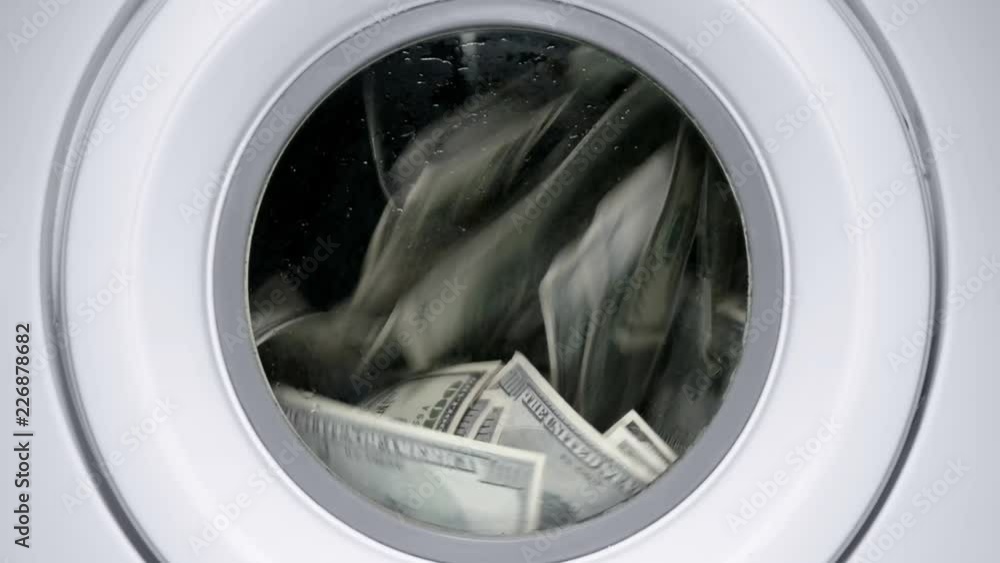in a drum of a washing machine, money and dollars are spinning and laundered, close-up in a drum of a washing machine, money and dollars are spinning and laundered, close-up