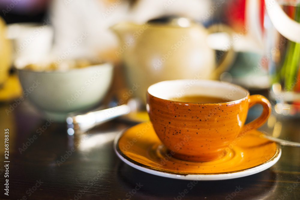 Fototapeta premium a Cup of tea in the cafe, an orange mug on the table, a mug on the table