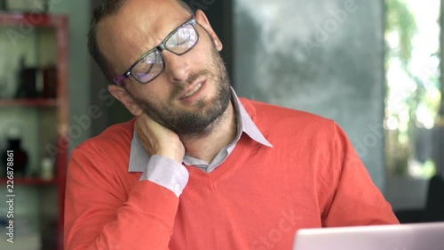 Young man having neck pain during work on laptop at home
 photo