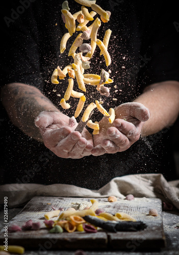 Fotografie close hand make pasta toss on a black background before cooking the dish