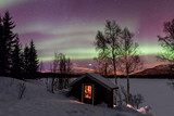 Northern Lights over a frozen snowy lake, the barn in the foreground. Norway, Lofoten islands.