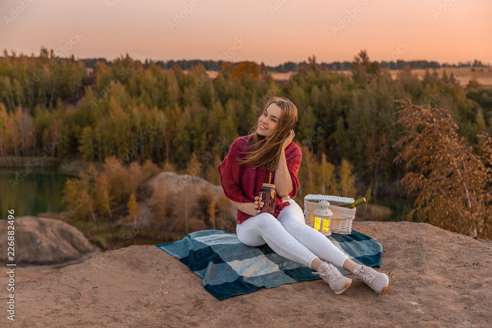 красивая девушка в красном свитере на пикнике на берегу красивого озера в горах.