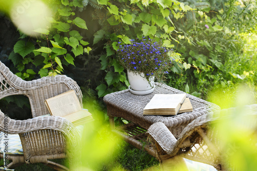 Wicker table, chairs and books in the garden at summer time