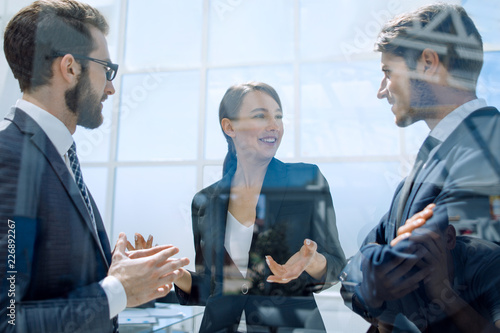 employees discussing work plan standing in office.