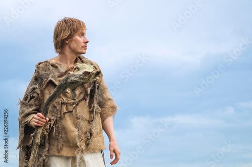 young shaman with a staff of an old stick on the background of a blue pre-storm sky