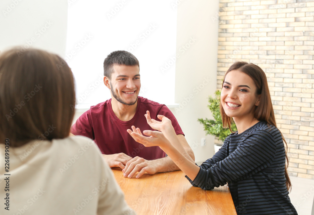 Group of young people sitting at table together, indoors. Unity concept Group of young people sitting at table together, indoors. Unity concept