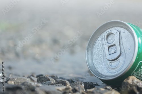Instant coffee to packed in tins is placed in water and has a rock foreground and white light in background with bokeh
