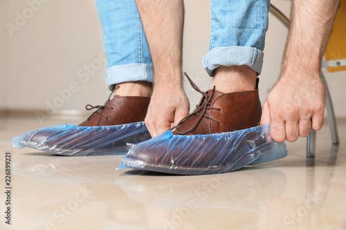Man putting on blue shoe covers, closeup