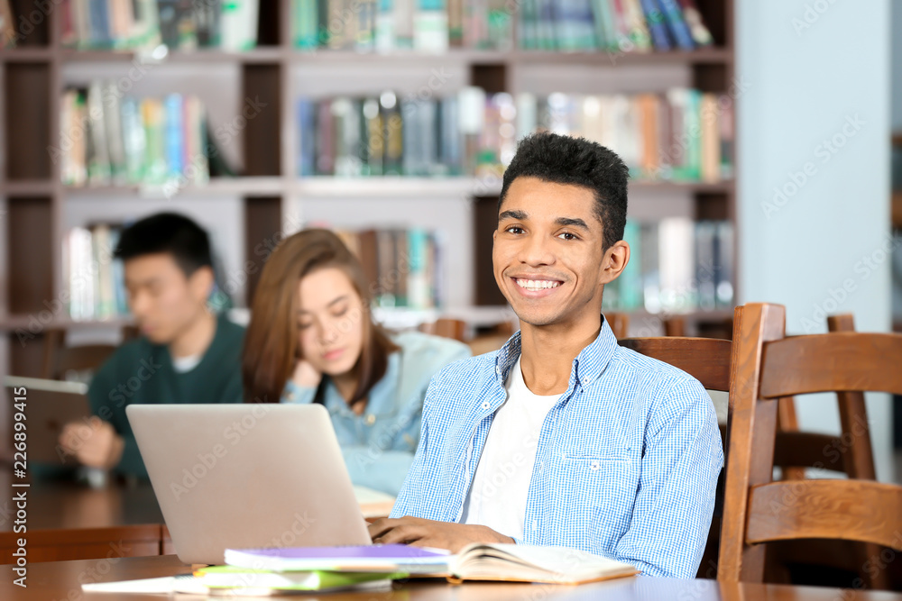 African American student with laptop studying in library African American student with laptop studying in library