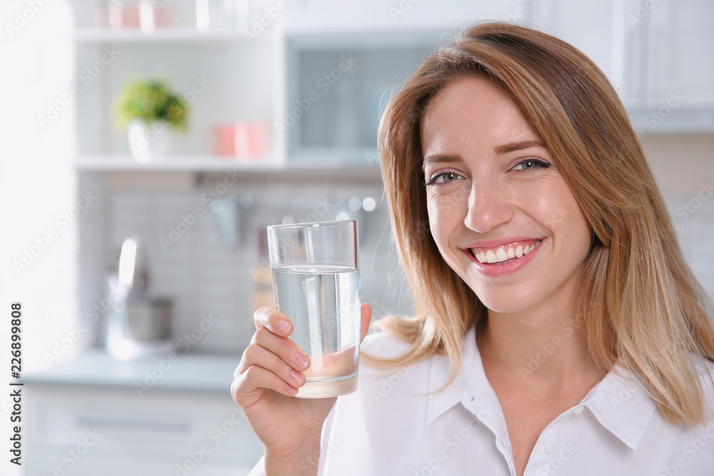 Young woman holding glass with clean water in kitchen Young woman holding glass with clean water in kitchen