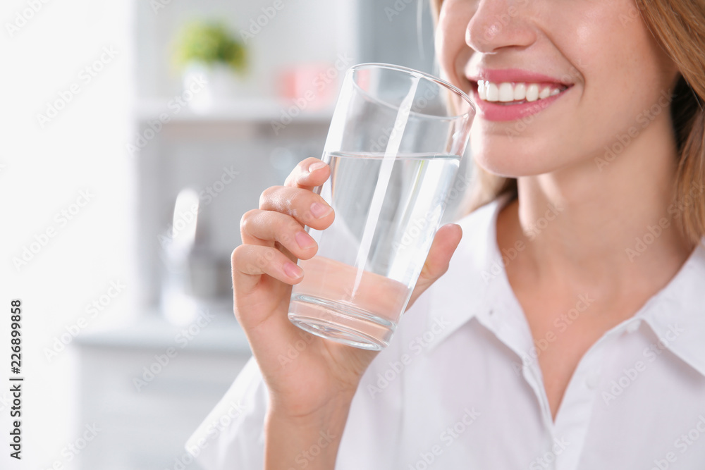 Woman drinking clean water from glass in kitchen, closeup Woman drinking clean water from glass in kitchen, closeup