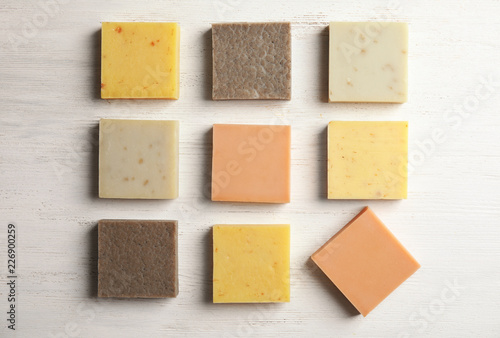 Hand made soap bars on white wooden background, top view