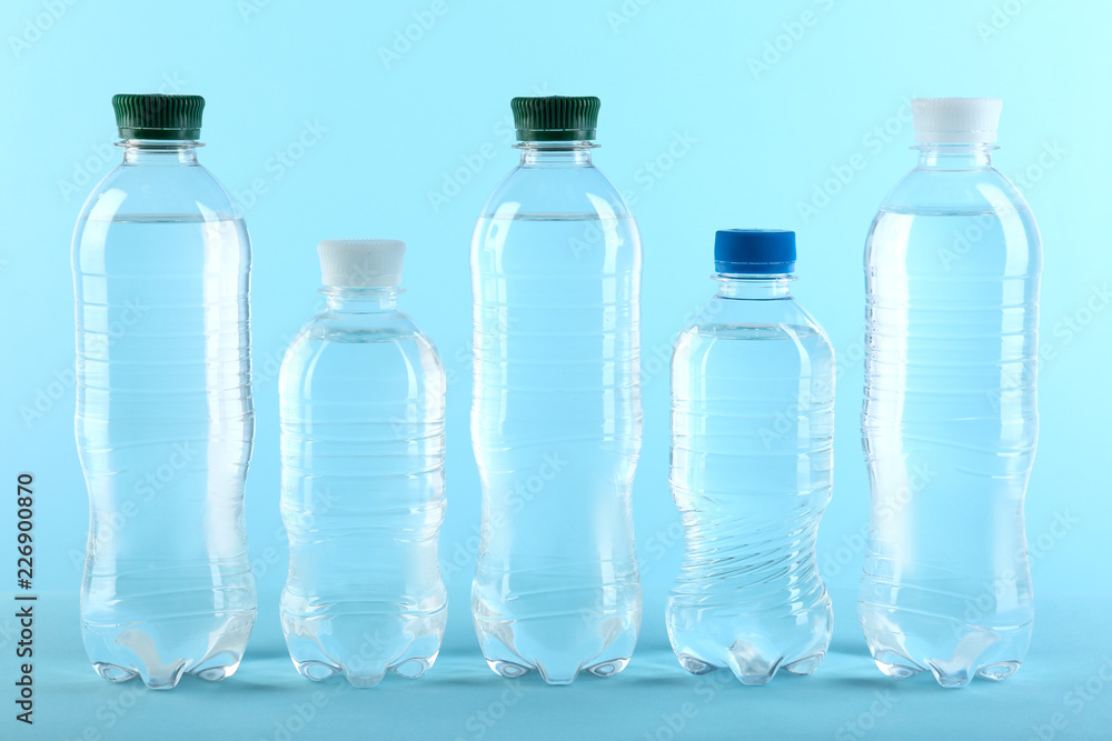 Row of different plastic bottles with water on color background Row of different plastic bottles with water on color background